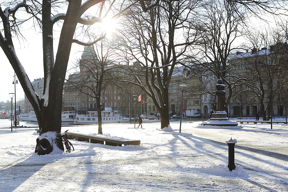 Sunshine in the snow-covered Berzelii Park, by the waterfront at Nybroviken, in Stockholm, Sweden, Scandinavia, Europe