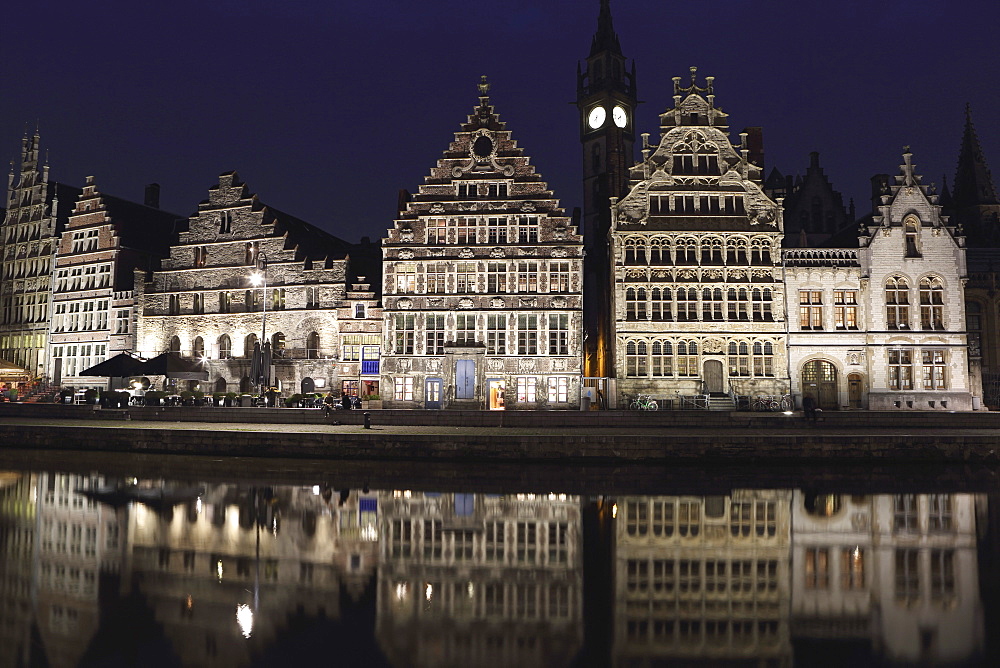 Gothic buildings on the waterfront Graslei reflect in the Leie canal, at night in central Ghent, Belgium, Europe