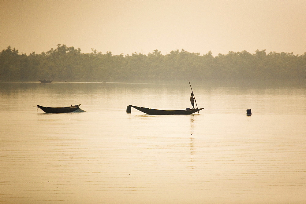 A man stands on a boat in the Sunderbans (Sundarbans) National Park, UNESCO World Heritage Site, West Bengal, India, Asia