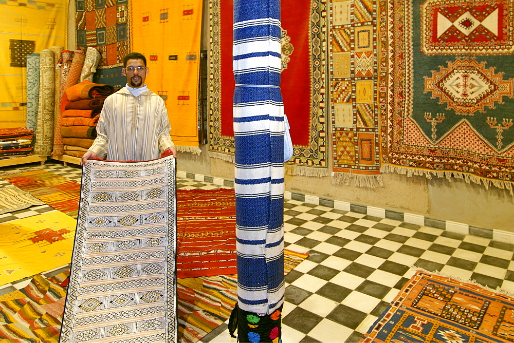 A shop keeper displays a carpet inside his shop in the Berber village of Merzouga in eastern Morocco