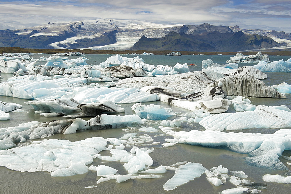 A tourist boat dwarfed by icebergs floating in Jokullsarlon lake at the foot of the Vatnajokull glacier, in the southeast, Iceland, Polar Regions