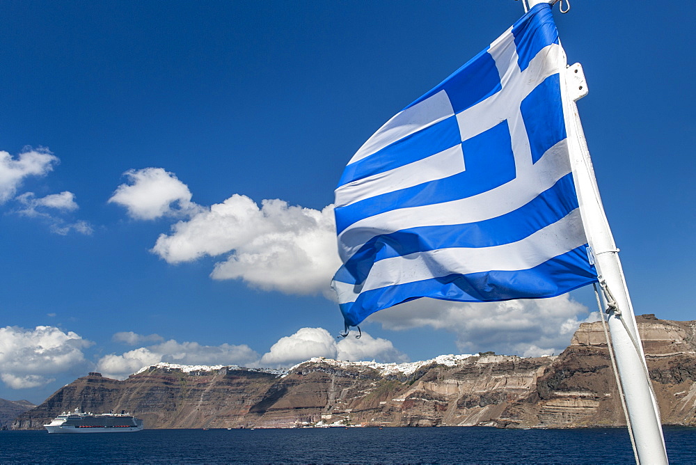 Greek flag seen against a view of Santorini island, Cyclades, Greek Islands, Greece, Europe