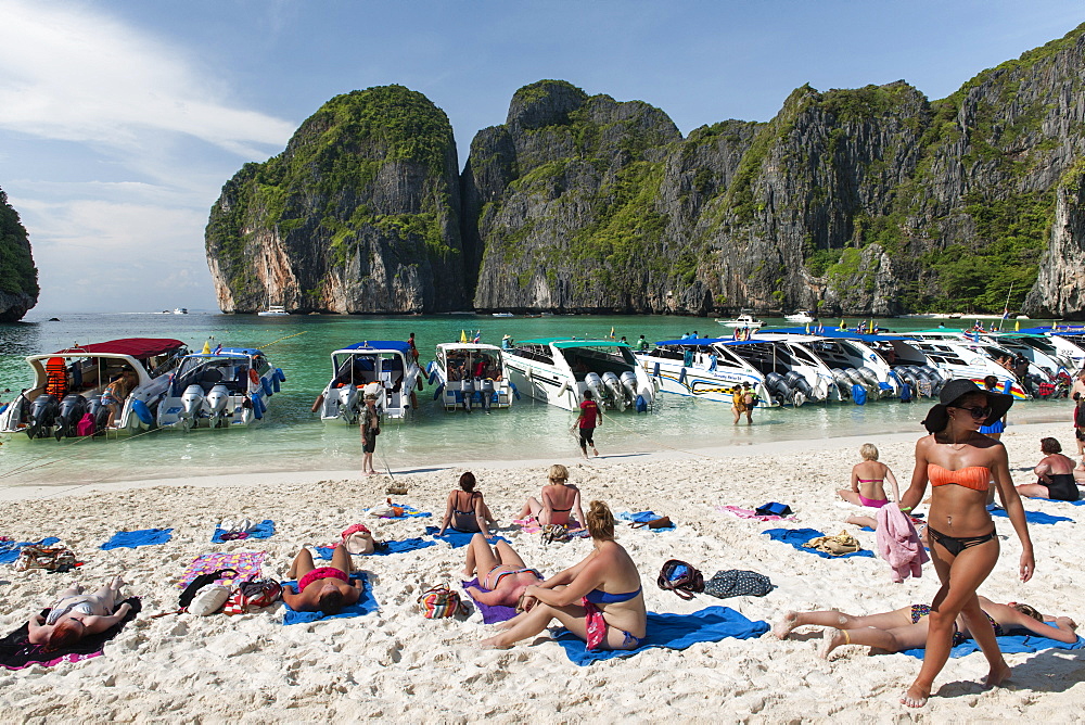 Tourist boats and tourists in Maya Bay on Koh Phi Phi Ley island in Thailand.