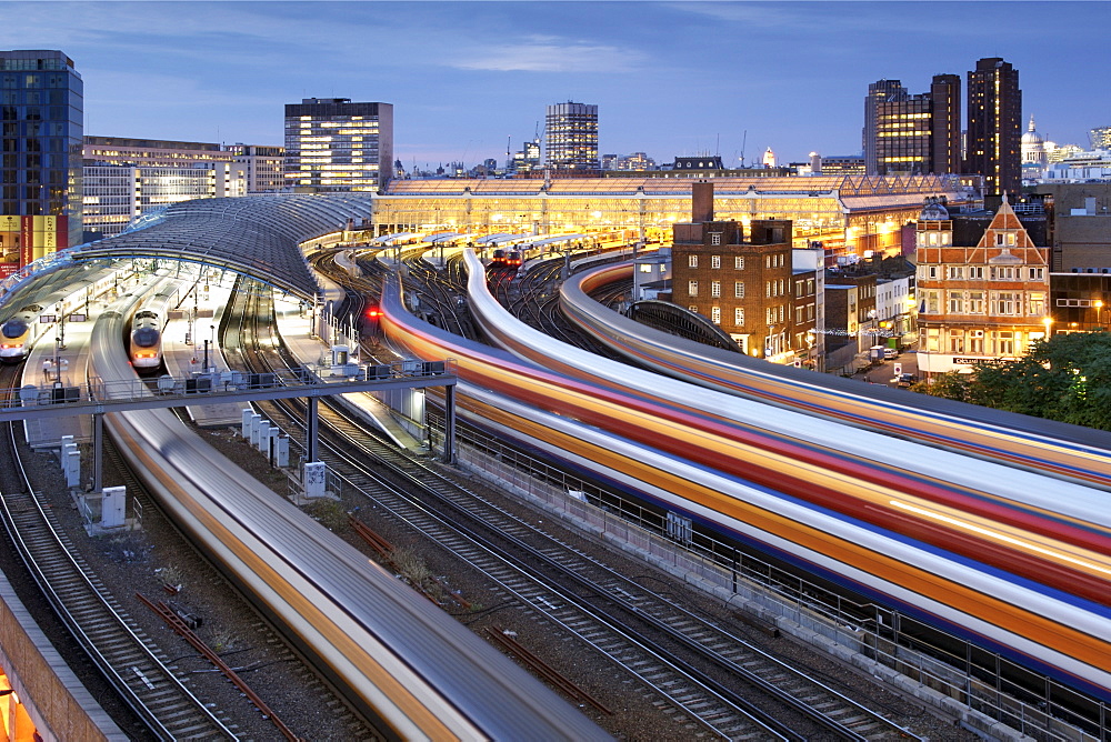 A blur of trains arriving and leaving London's Waterloo train station at dusk during rush hour.