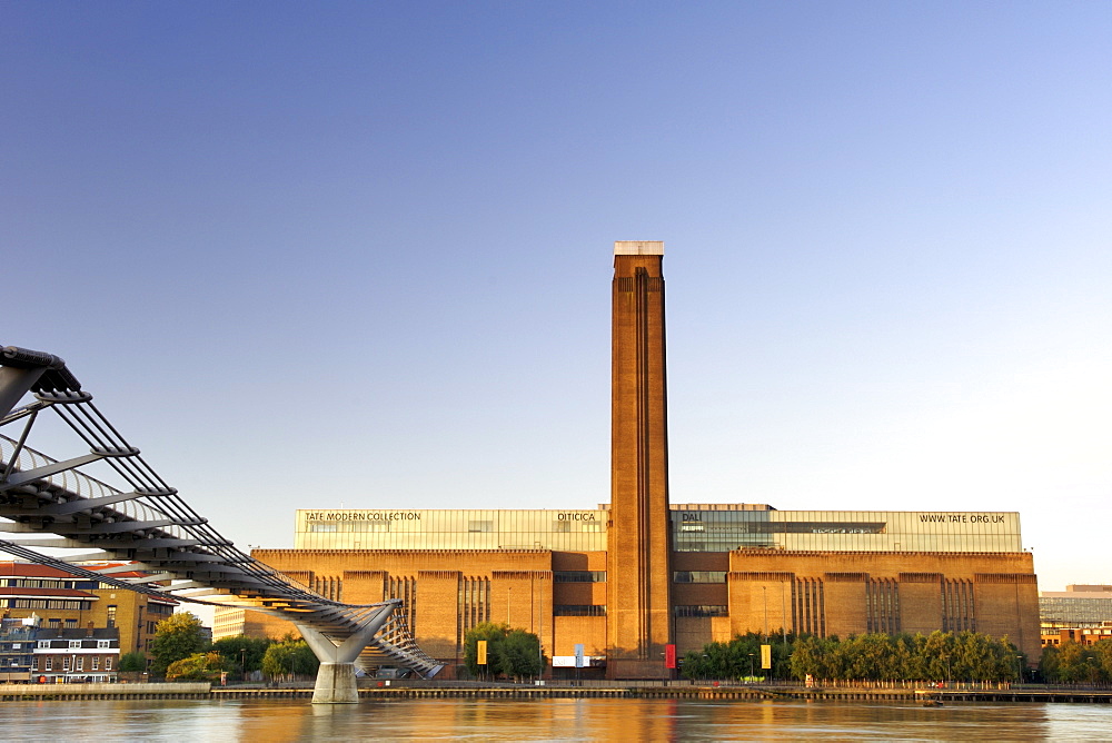 Early morning view of the Tate Modern art Gallery and Millenium Bridge taken from across the Thames River in London. The Tate Modern is the converted former Bankside power station on the south bank of the Thames River. It was built in two phases between 1947 and 1963 and was designed by Sir Giles Gilbert Scott.