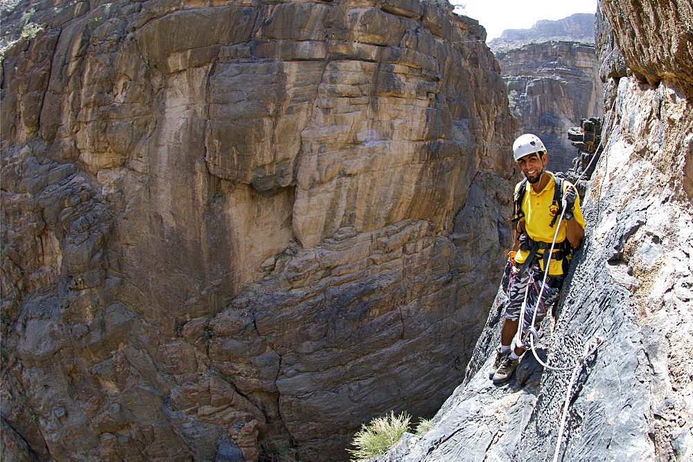 A man doing the Via Ferrata hike in Snake Canyon, part of Wadi Bani Auf in Jebel Akhdar of the western Hajar mountains in Oman.