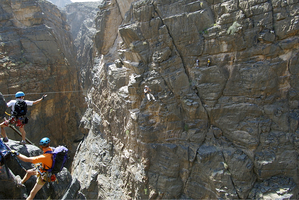 A hiker traversing a zip-wire (aka flying fox) on the Via Ferrata hike in Snake Canyon, part of Wadi Bani Auf in Jebel Akhdar of the western Hajar mountains in Oman.