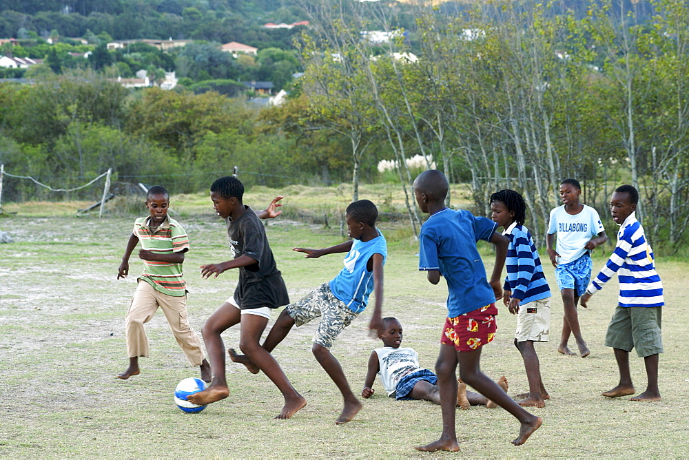 African children playing soccer barefoot in a field in Hout Bay in Cape Town, South Africa.