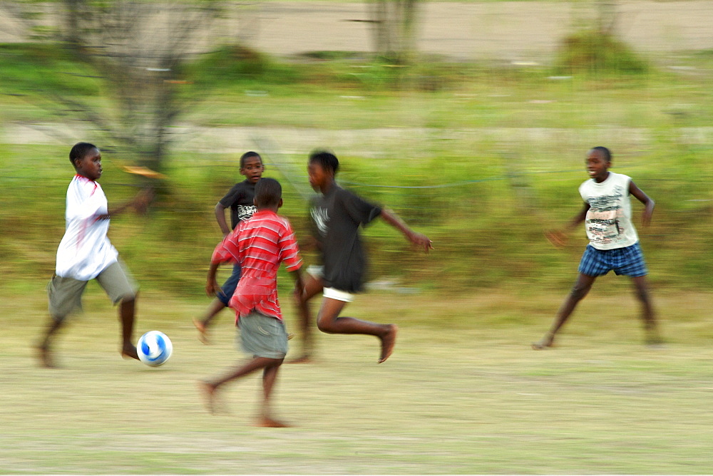 African children playing soccer barefoot in a field in Hout Bay in Cape Town, South Africa.