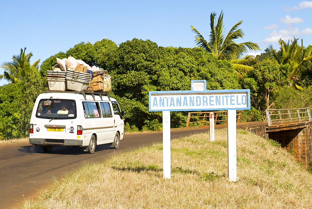 Taxi brousse (bush taxi) driving past a road sign for the village of Antanandrenitelo in northern Madagascar, Madagascar, Africa