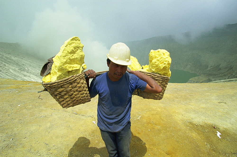 Miner on the crater rim of 2400m volcano of Gunung Ijen in east Java, Indonesia, Southeast Asia, Asia