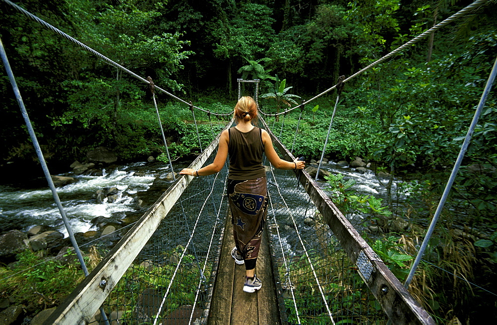 Hiker crossing a river on the Lavena Coastal Walk in this famous national park on the south coast of Taveuni - the 'Garden Island', Bouma National Park, Taveuni, Fiji