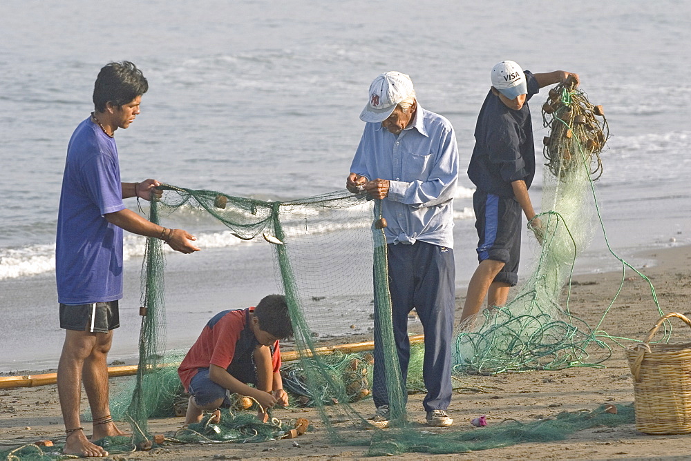 Fishing family on the beach at the popular far north coast fishing & surfing village of Huanchaco, near Trujillo, Peru, South America.