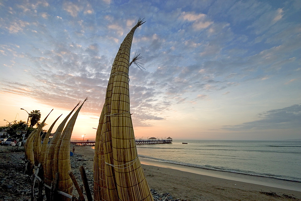 Sunset behind 'caballitos (little horses) de totora' reed boats at the popular far north coast fishing & surfing village of Huanchaco, near Trujillo, Peru, South America.