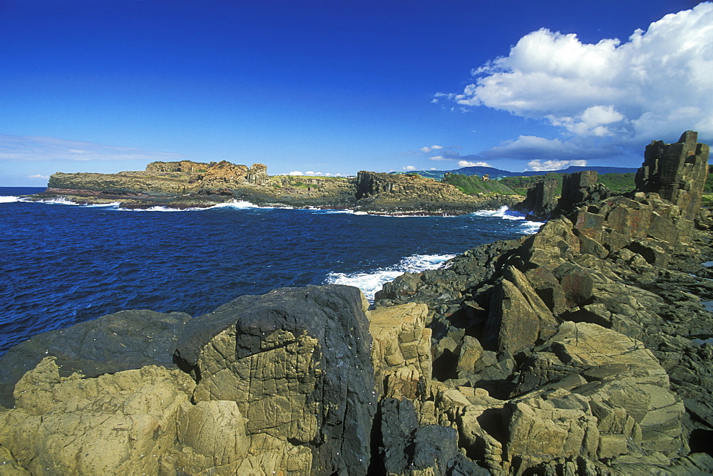 Columnar structures, created during cooling of basalt lava, with an intrusion or dyke of darker rock in the foreground, near Bombo Beach, Kiama, south coast, New South Wales, Australia, Pacific