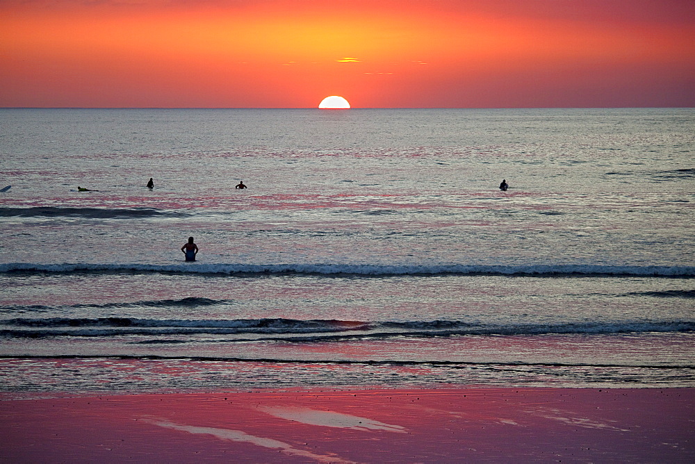 Surfers and swimmers at sunset off Playa Guiones beach, Nosara, Nicoya Peninsula, Guanacaste Province, Costa Rica, Central America