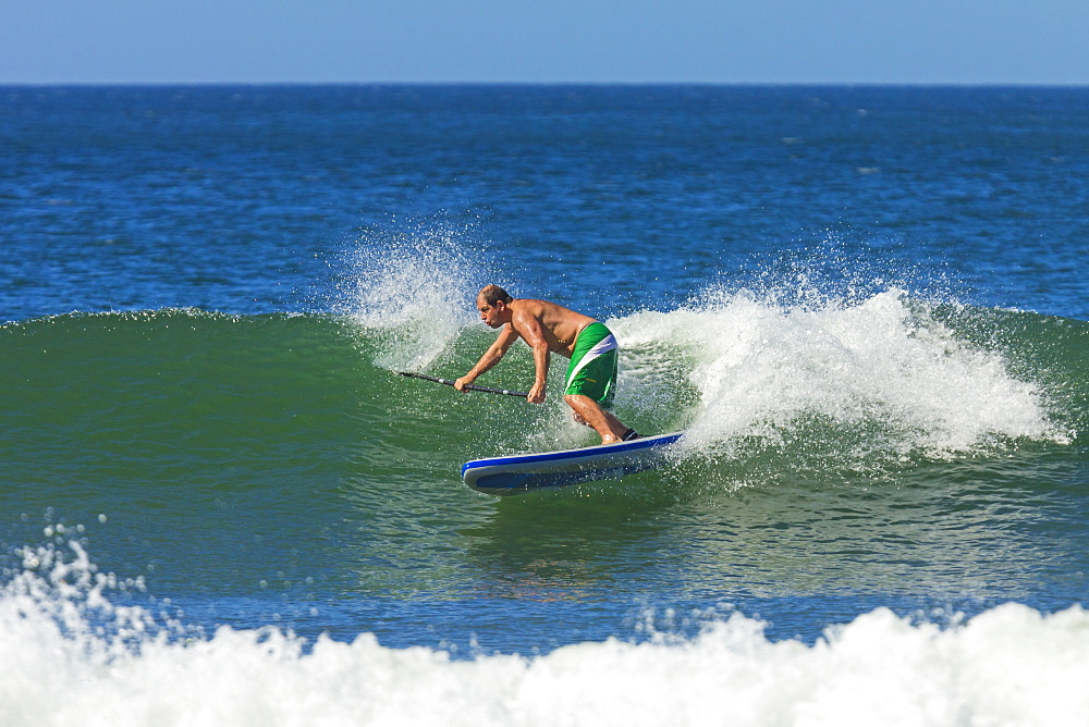 Man surfing inflatable paddle board at Playa Guiones beach, Nosara, Nicoya Peninsula, Guanacaste Province, Costa Rica, Central America