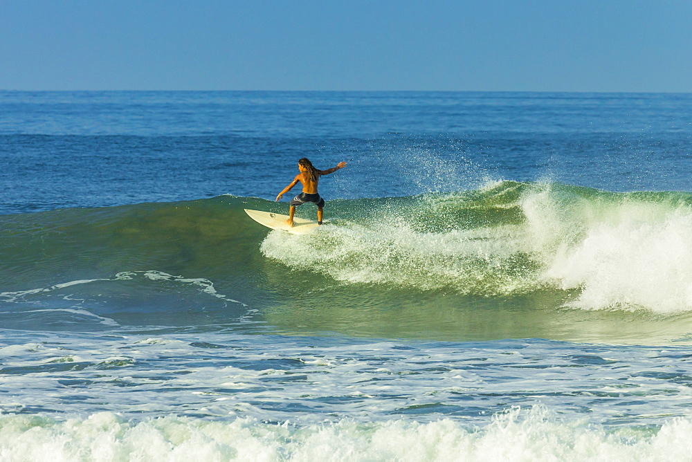 Surfer riding a wave at popular Playa Guiones surf beach, Nosara, Nicoya Peninsula, Guanacaste Province, Costa Rica, Central America