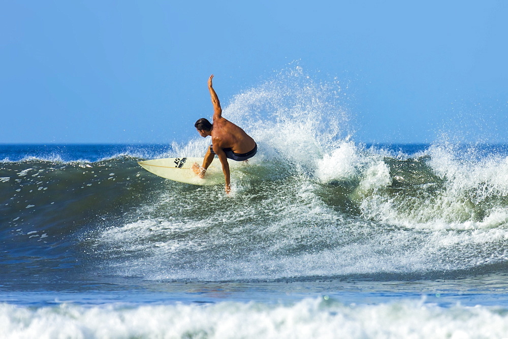 Surfer on shortboard riding wave at popular Playa Guiones surf beach, Nosara, Nicoya Peninsula, Guanacaste Province, Costa Rica, Central America