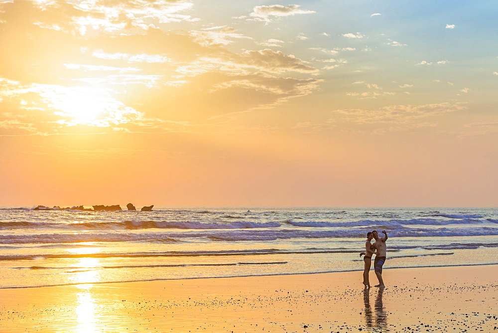 Couple photographing themselves at sunset, Playa Guiones surf beach, Nosara, Nicoya Peninsula, Guanacaste Province, Costa Rica, Central America