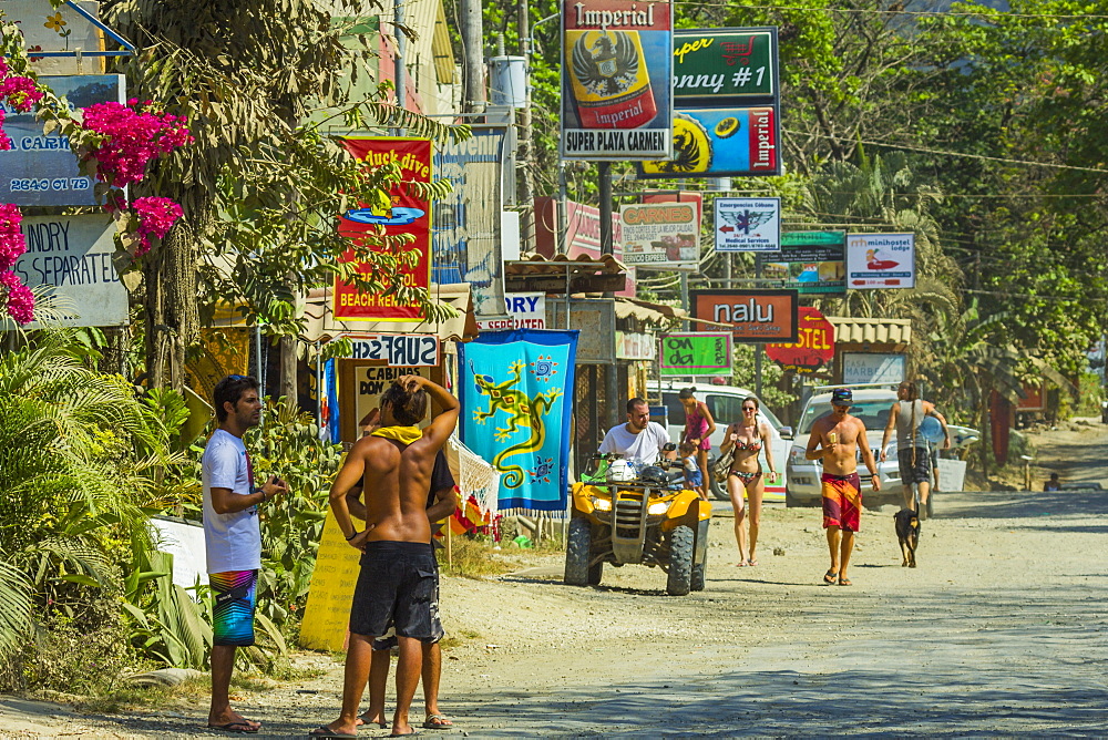 Tourists and signs on the main strip at this busy south coast of Nicoya Peninsula resort, Santa Teresa, Puntarenas, Costa Rica, Central America