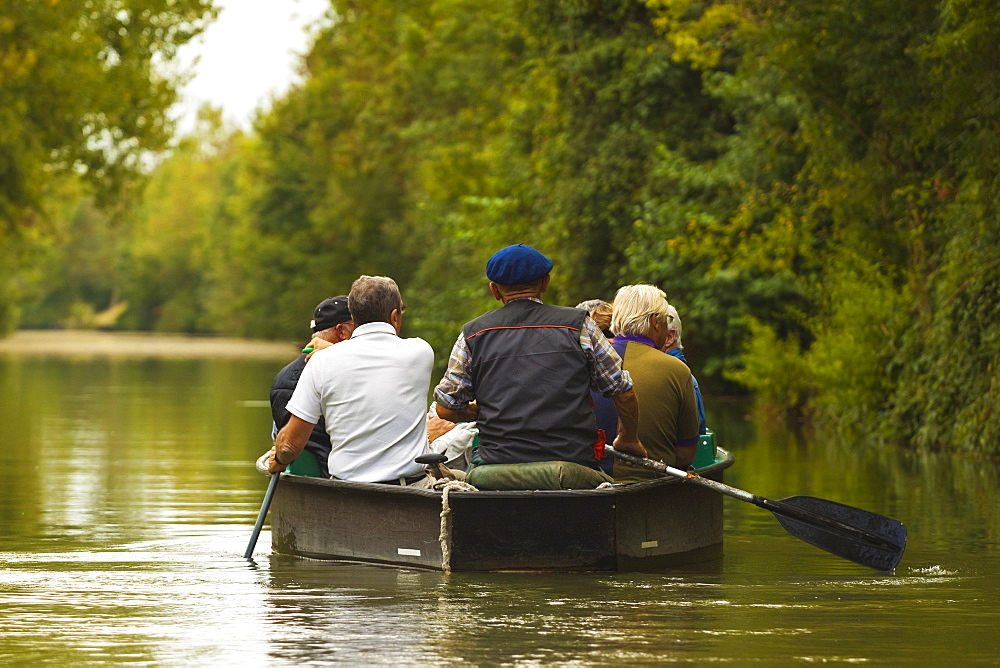 Tourists paddling boat in the Marais Poitevin (Green Venice) wetlands, Arcais, Nouvelle-Aquitaine, France, Europe