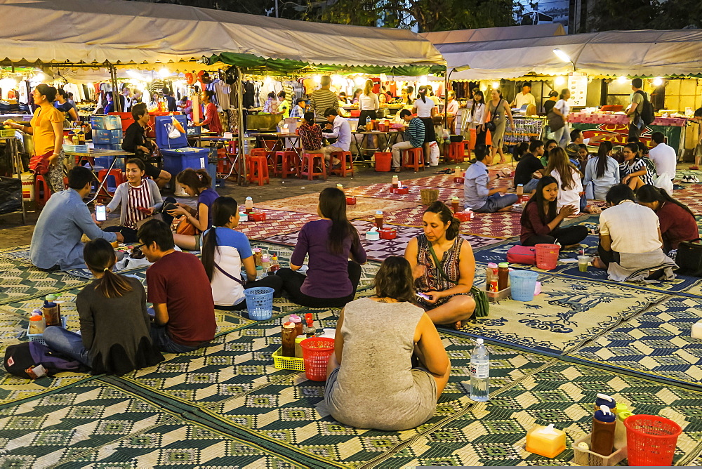 People seated on mats eating at the colourful Phsar Kandal night market near the riverfront, City centre, Phnom Penh, Cambodia, Indochina, Southeast Asia, Asia