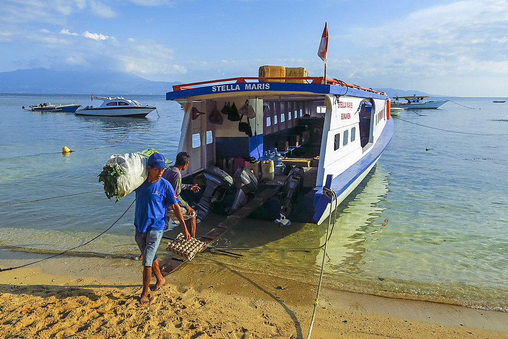 Men unload cargo from ferry at this coral fringed holiday island and scuba diving destination. Bunaken, North Sulawesi, Indonesia, Southeast Asia, Asia