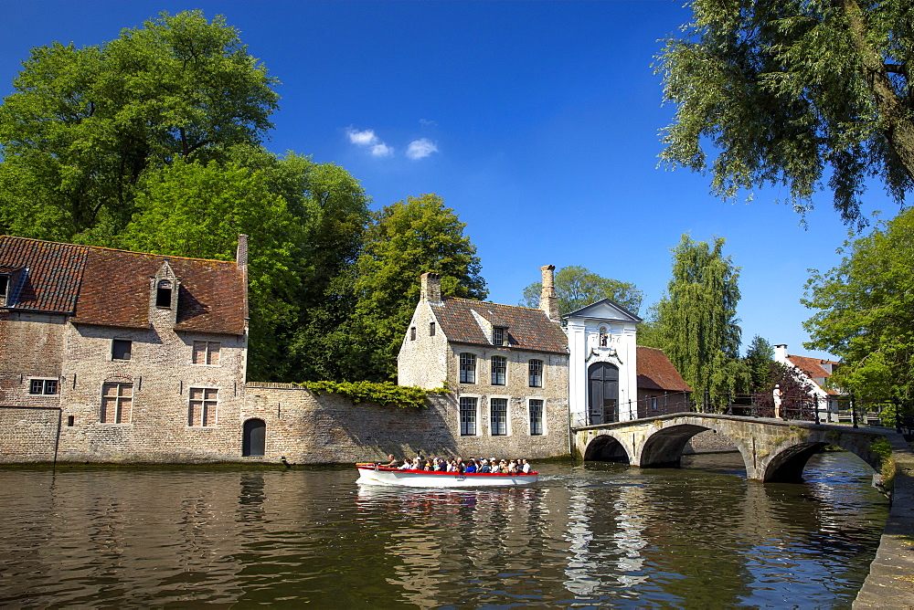 Tourist boat, at the Minnewater Lake and Begijnhof Bridge with entrance to Beguinage, Bruges, Belgium, Europe