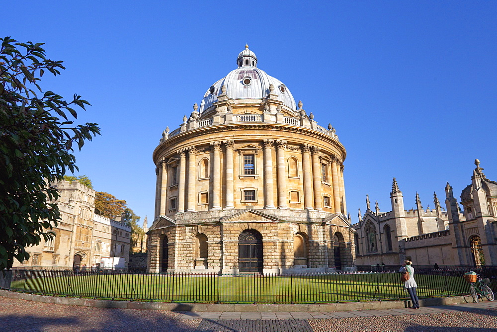 Student with bicycle in front of Radcliffe Camera and All Souls College, Oxford University, Oxford, Oxfordshire, England, United Kingdom, Europe