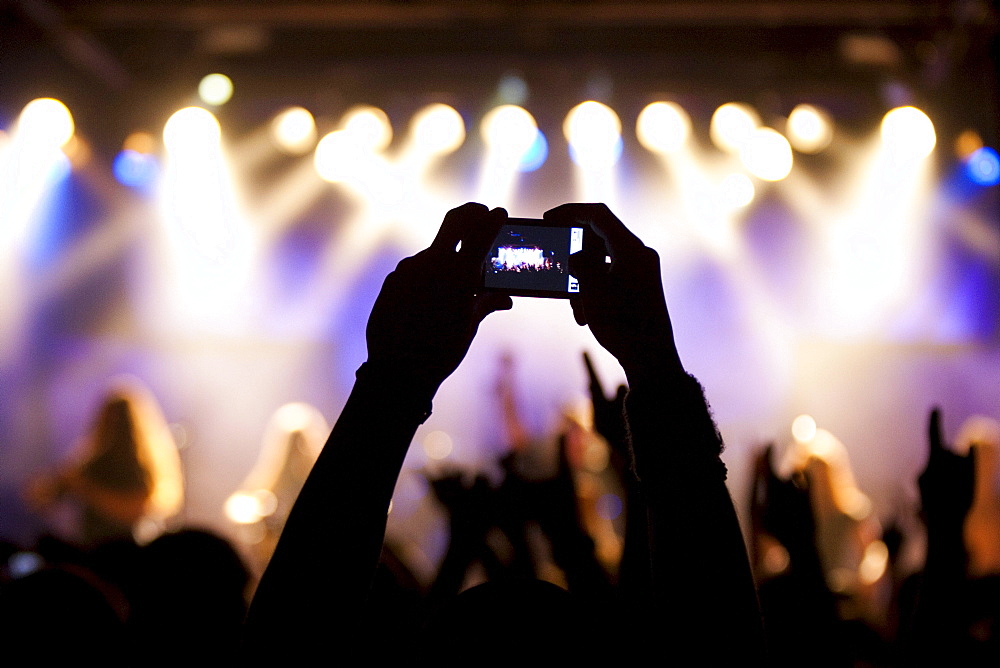 A fan takes a picture with small digital camera at the concert of Swiss pagan metal band Eluveitie live in the Schueuer venue, Lucerne, Switzerland