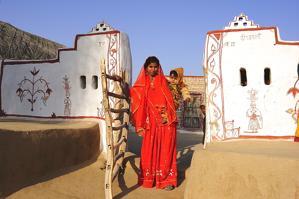 Woman in a sari with a toddler, traditionally painted entrance to a courtyard, Thar Desert, Rajasthan, North India, India, Asia