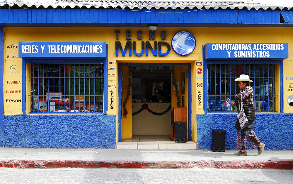 A man with traditional dress passes by a telecommunication shop, Solola Department, Guatemala, Central America