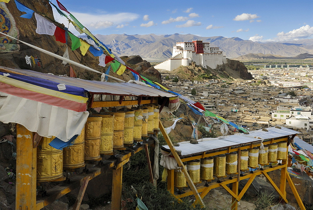 Prayer wheels, view over the historic town centre and the rebuilt Shigatse Dzong fortress, Shigatse, Tibet, China, Asia