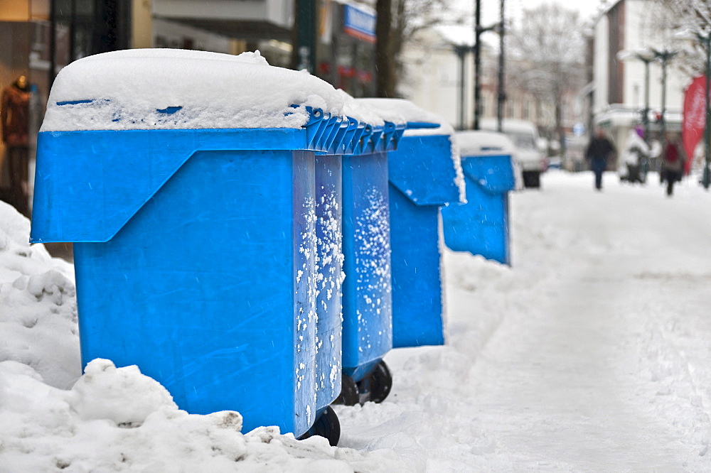 Blue refuse bins standing on the side of the road in the snow, Germany, Europe