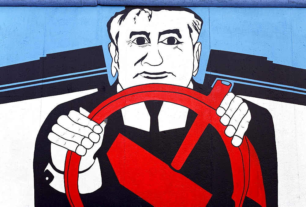 Gorbachev sitting behind a steering wheel made from the Communist hammer symbol, painting on the remants of the Berlin Wall, Friedrichshain district, Berlin, Germany, Europe