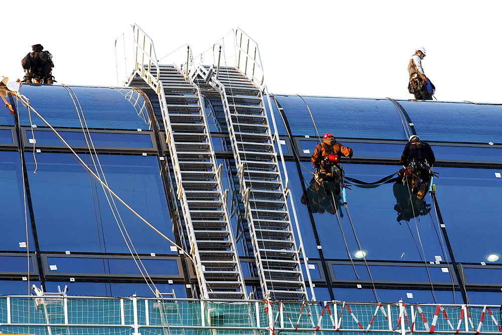 Roped up roofers mounting large glass elemtens onto a dome roof, Berlin, Germany, Europe