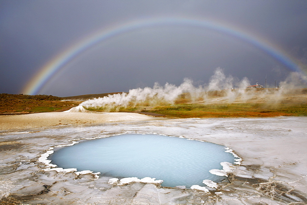 Blahver, blue spring, the most beautiful blue water pool in Hveravellir in the Highlands, in front of Oeskjuholt, a steaming calc-sinter mound which looks like a mini volcano, below a rainbow, Hveravellir, Iceland, Europe