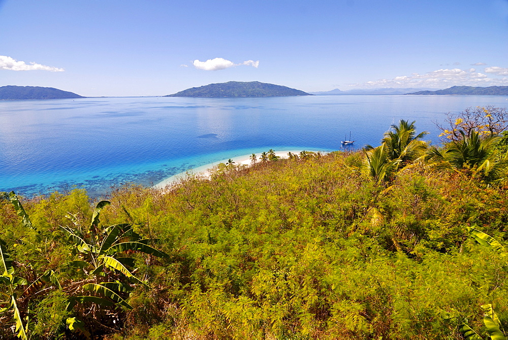 The crystal clear waters and white sand beach of Nosy Tanikely, in the distance, Nosy Komba, Nosy Be, Madagascar, Africa