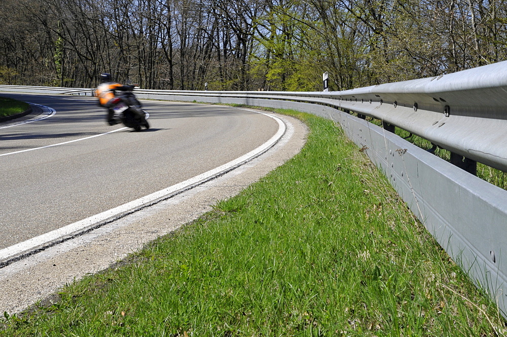 Motorcyclist in a curve on a country road with guard rail for protection, Eifel, Germany, Europe