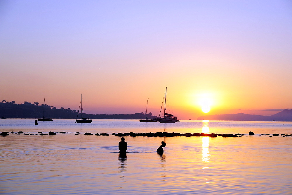 People bathing at sunrise, boats in the Bay of Puerto de Pollensa, Port de Pollenca, Majorca, Balearic Islands, Mediterranean Sea, Spain, Europe