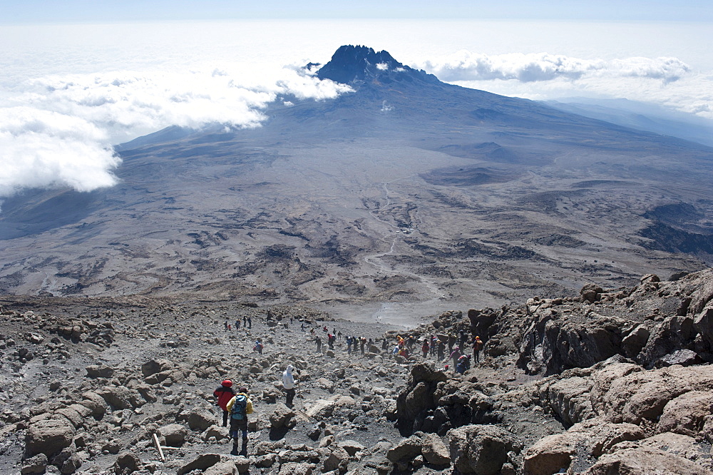 Trekking, mountain climbing, view from the crater rim towards climbers descending towards Kibo Hut at the Kibo Saddle, in the distance, the peak of Mount Mawenzi surrounded by clouds, Kilimanjaro, Marangu Route, Tanzania, East Africa, Africa