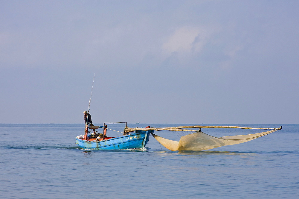 Fisherman returning his boat and fishing net from the sea, Phu Quoc Island, Vietnam, Southeast Asia