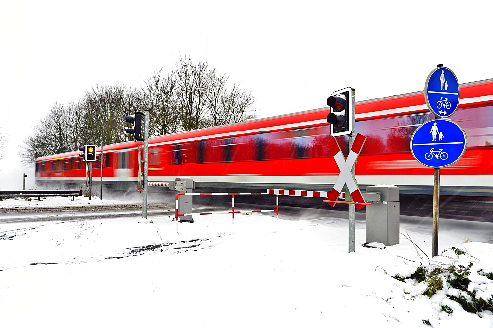 Passenger train passing a level crossing in winter, Grevenbroich, North Rhine-Westphalia, Germany, Europe