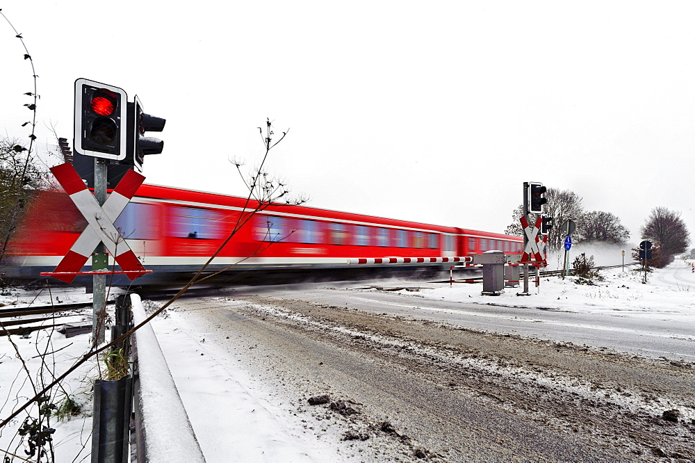 Passenger train passing a level crossing in winter, Grevenbroich, North Rhine-Westphalia, Germany, Europe