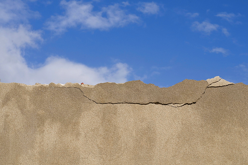 Coping of a wall with cracks against a blue sky