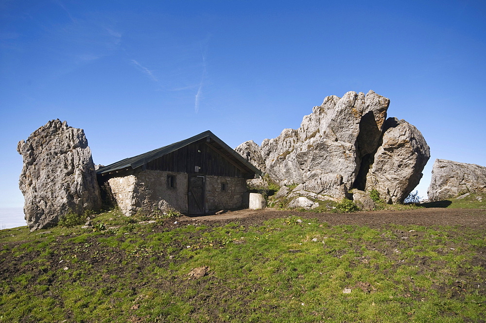 Stone house on Steinlingalm alp, built next to large limestone rocks, Kampenwand mountain massif, Chiemgau, Kampenwand mountain, Upper Bavaria, Germany, Europe