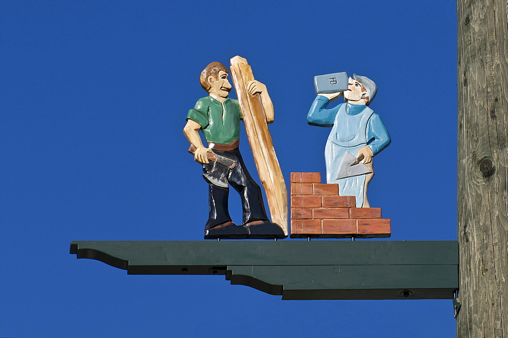 Detail of a traditional maypole, maypole figures of craftsmen, carpentry and masonry