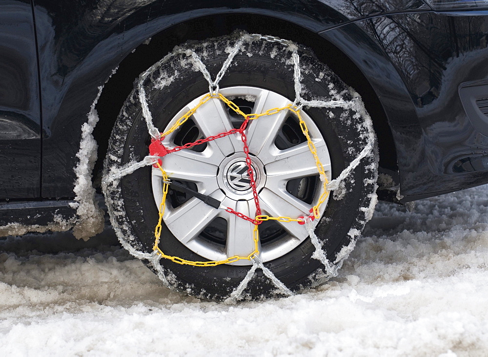 Car tyre with mounted snow chains in the snow