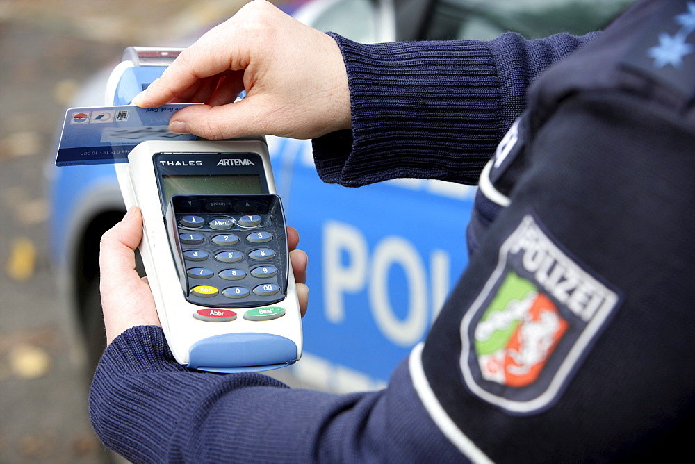 Police officer with BARVUS device for cashless payment of caution money, fines, tickets with credit card